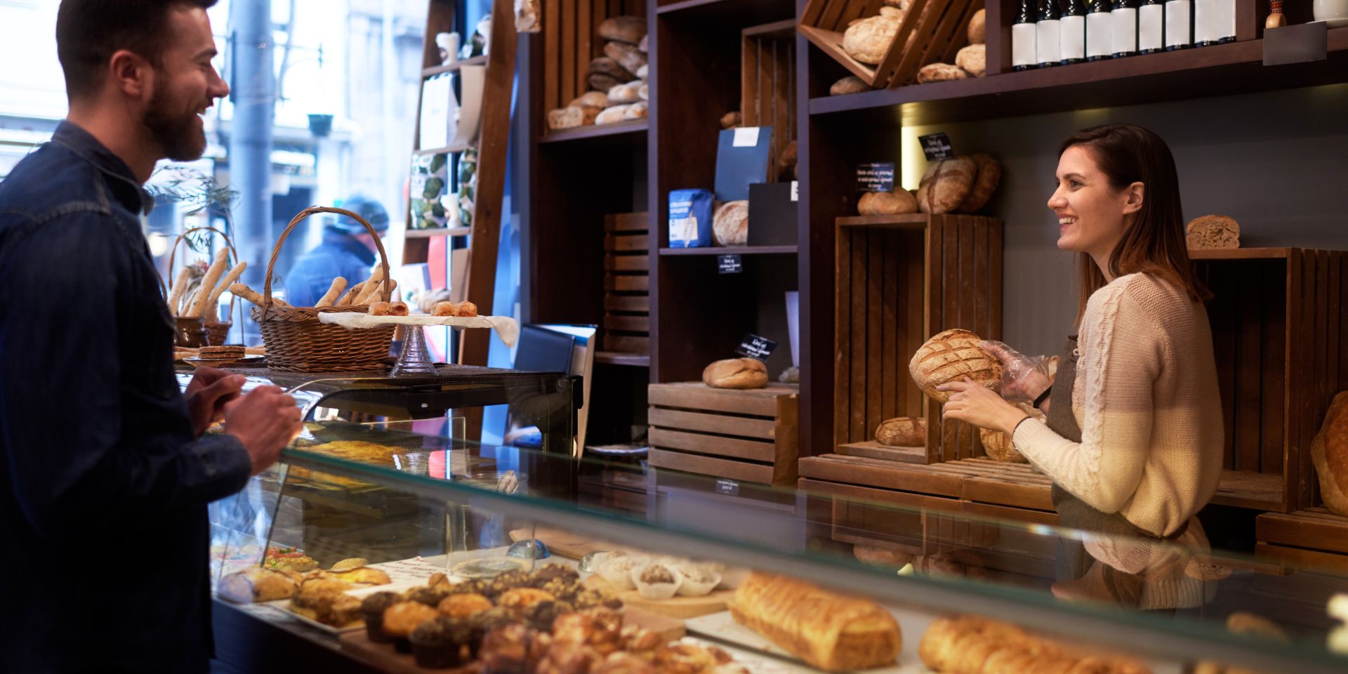 woman serving customer at a small bakery used on a page about business continuity insurance